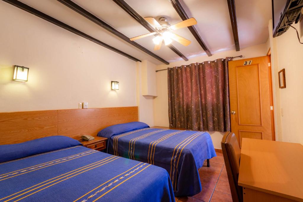 a hotel room with two beds and a table at Hotel el Carmen in Morelia