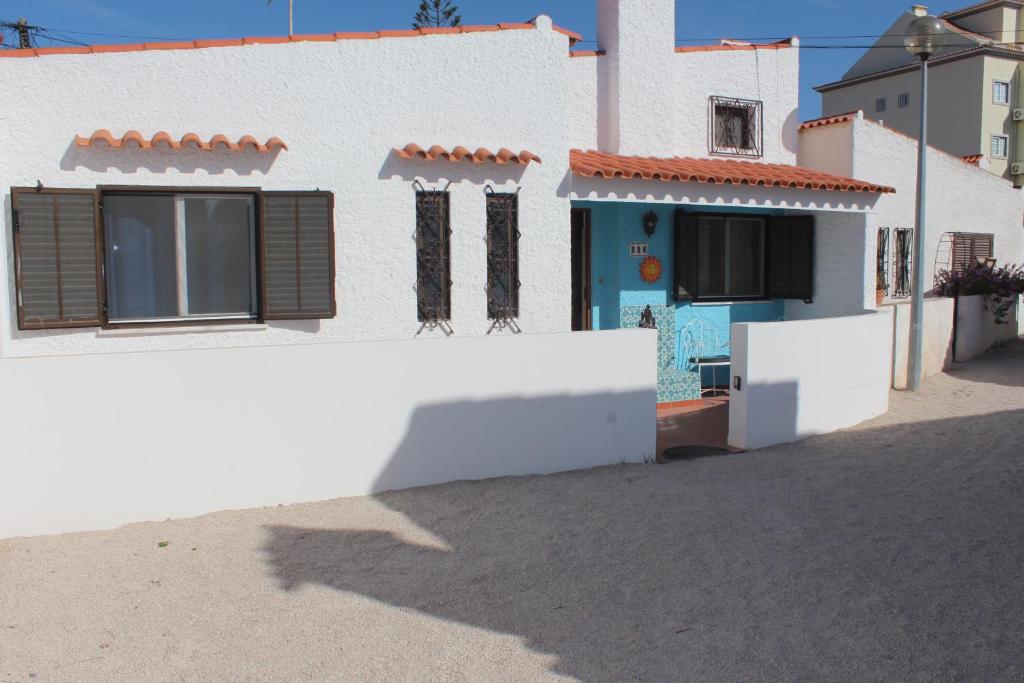 una casa blanca con una puerta azul en una calle en Recanto do Sol, en Hortas