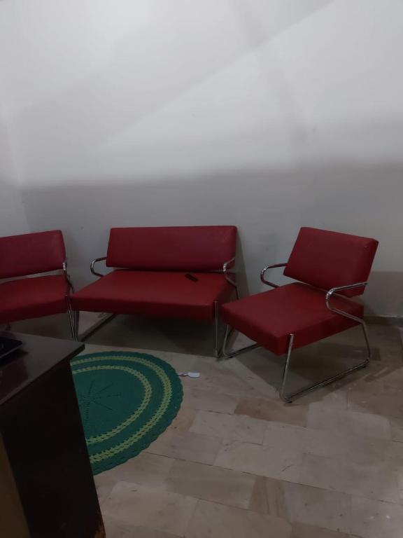 a waiting room with two red chairs and a green rug at Casa de férias in Conceição da Barra