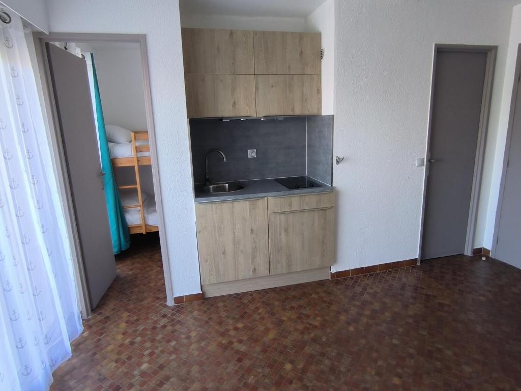 an empty room with a kitchen with a sink at Studio Cabine in Gruissan