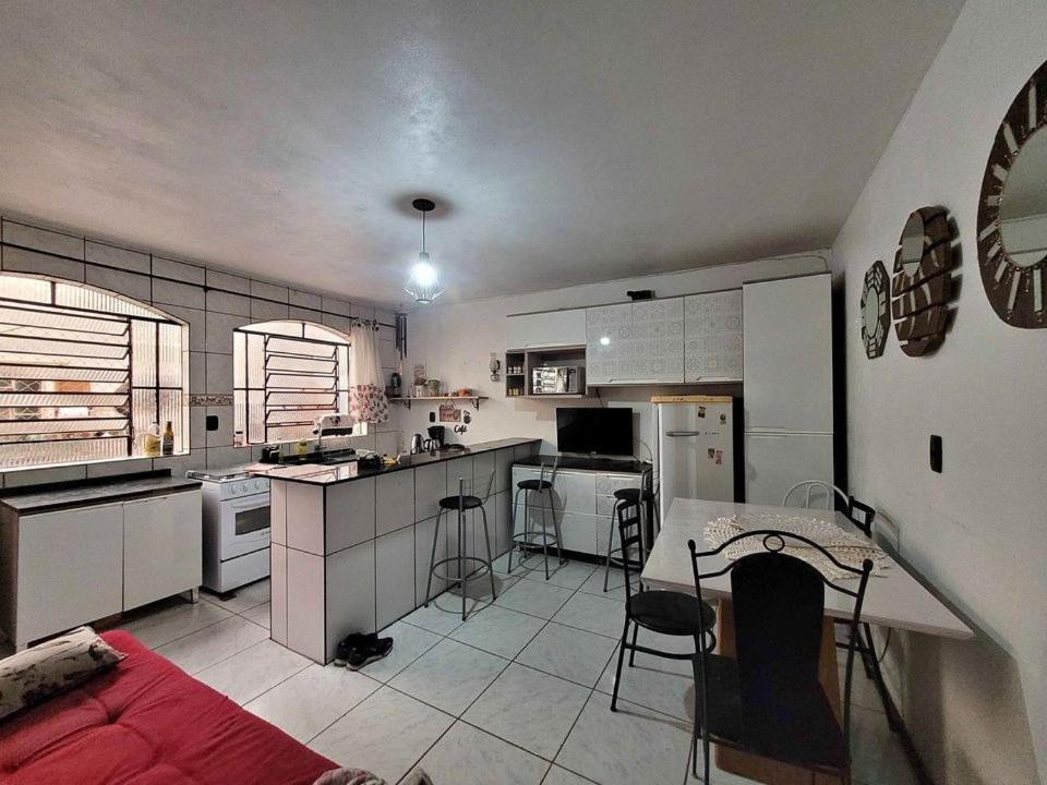 a kitchen with white cabinets and a table and chairs at Quarto em casa a 1.4km da UFSM in Santa Maria