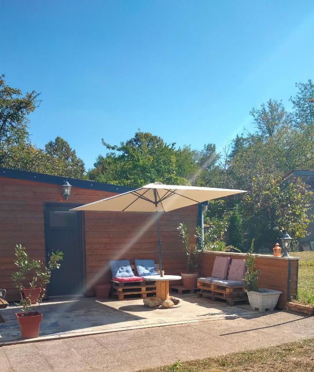 une terrasse avec un parasol, une table et des bancs dans l'établissement Maison Cosne sur Loire, à Cosne-Cours-sur-Loire