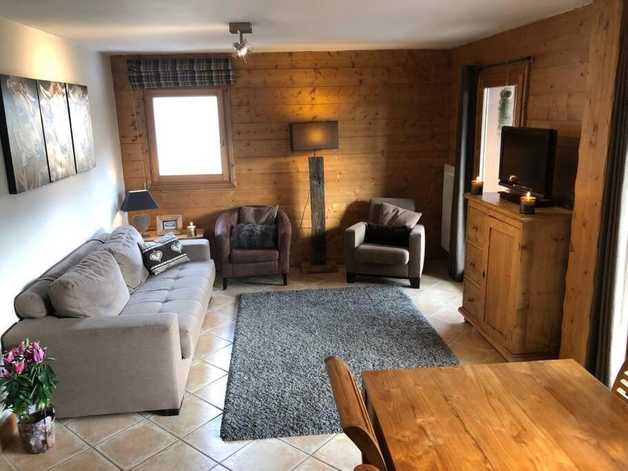 un salon avec un canapé, des chaises et une table dans l'établissement Superbe appart cosy, piscine terrasse, ascenseur., à Cohennoz