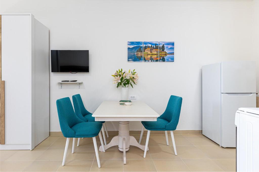 una cucina con un tavolo bianco e sedie blu di Apartments Lustica a Tivat