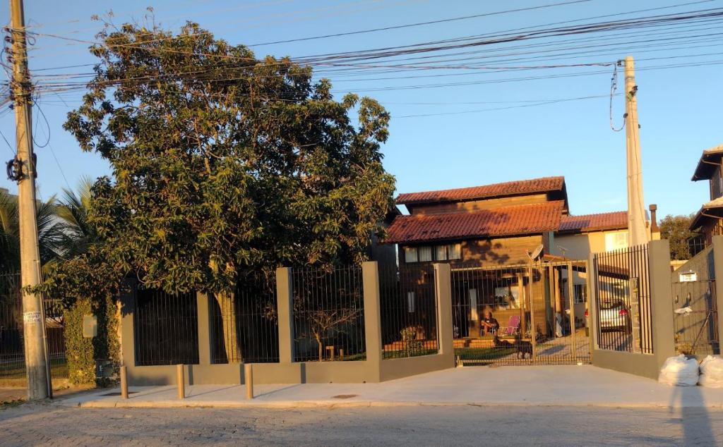 a fence with a tree in front of a building at Quintal Residencial in Florianópolis