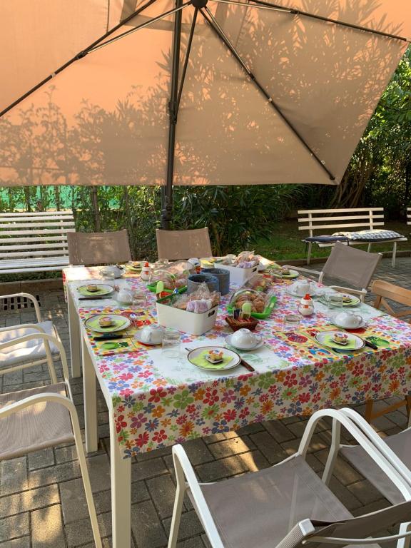 een tafel met eten, stoelen en een paraplu bij B&B La Salina in Cannuzzo