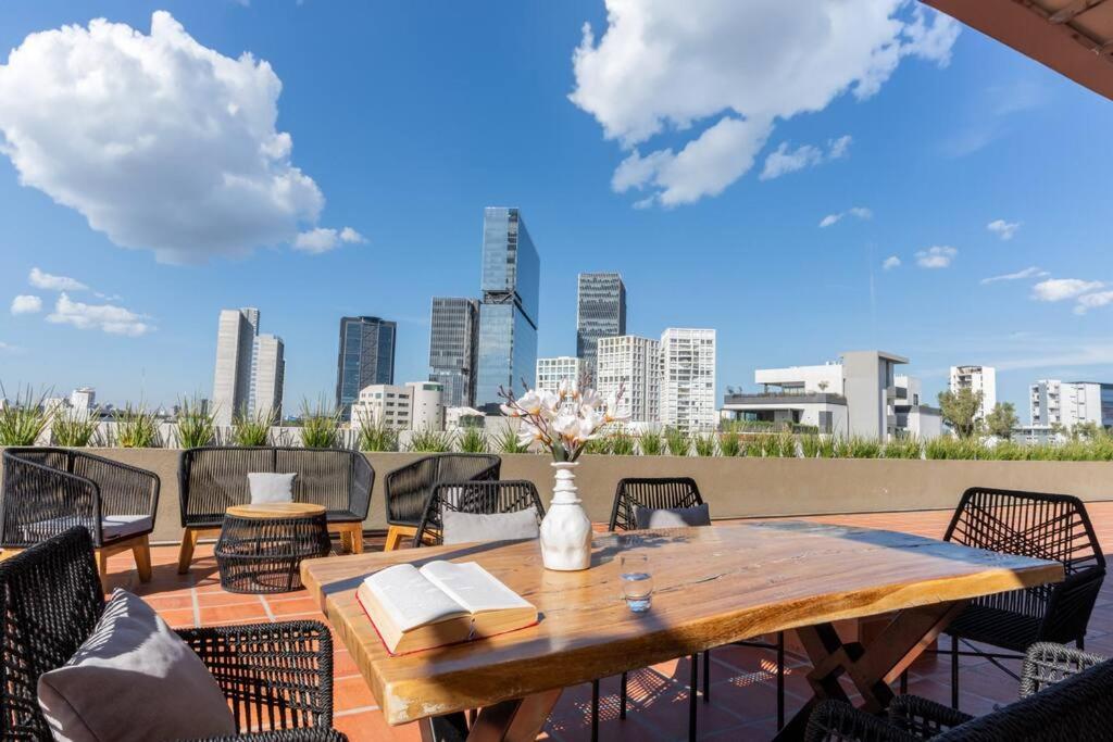 a wooden table and chairs on a patio with a city skyline at Amazing view with RoofGarden in Guadalajara