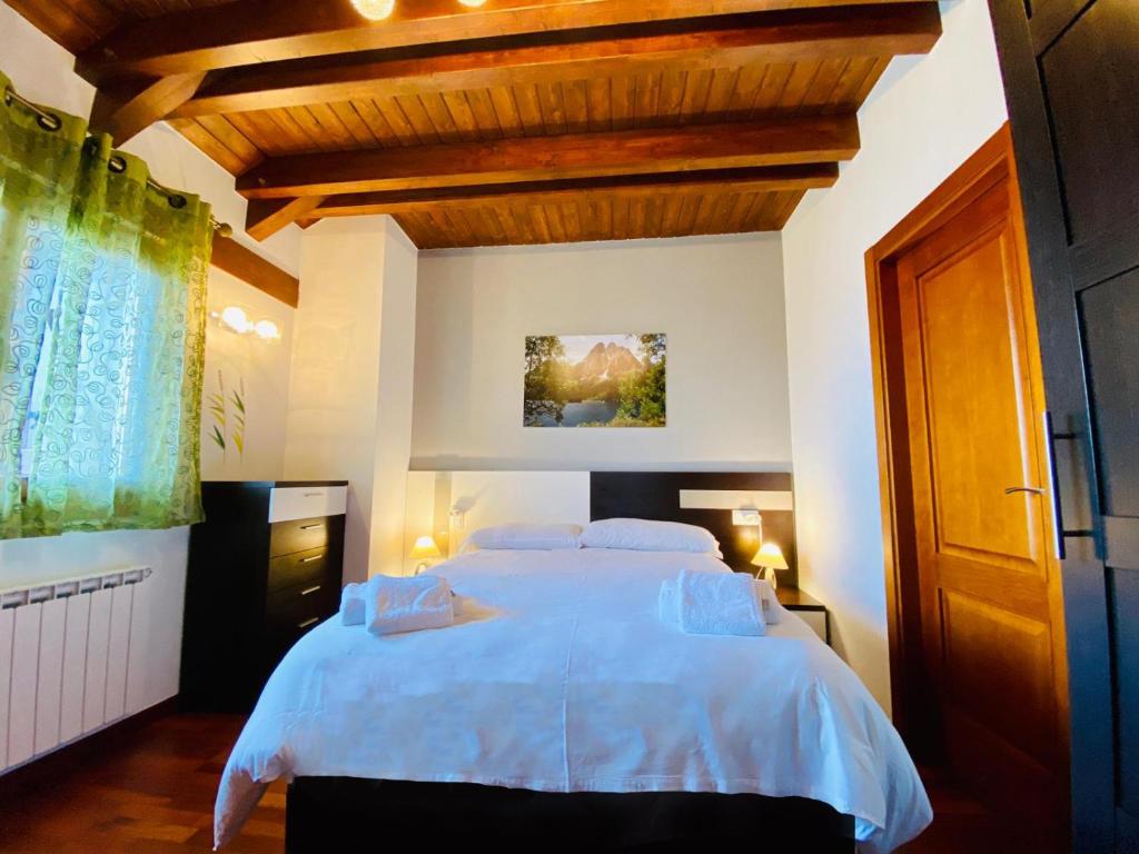 a bedroom with a large white bed with wooden ceilings at Casa Forn in Pujal