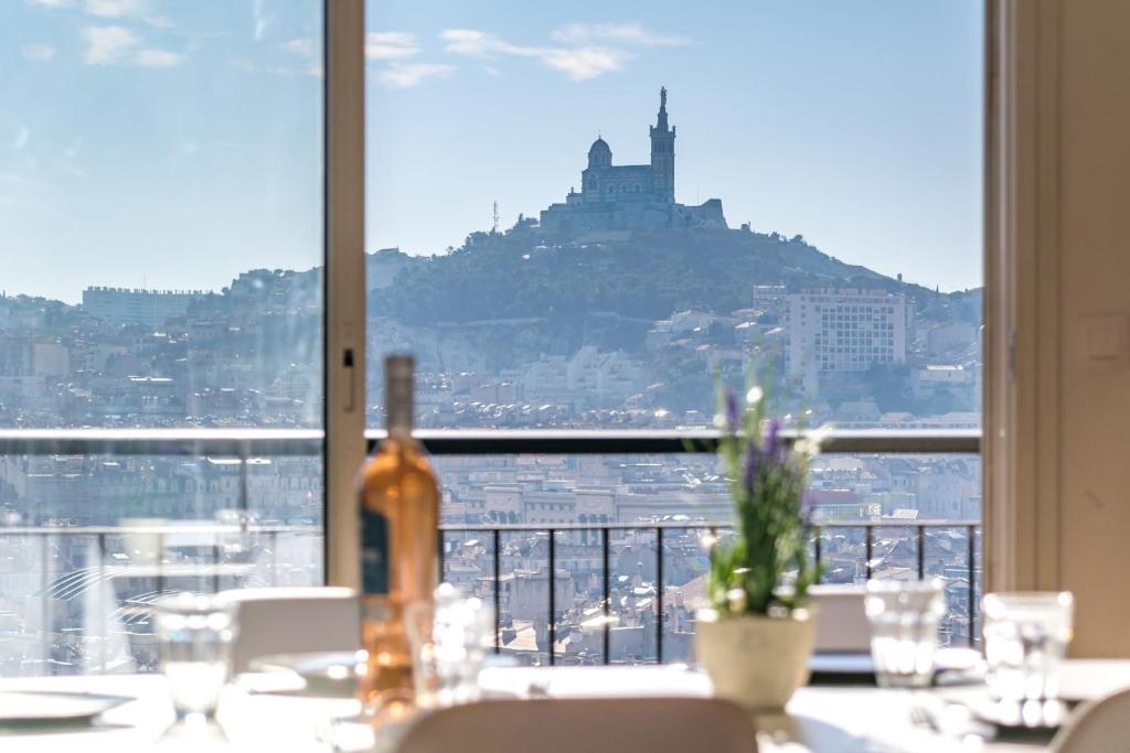 マルセイユにあるVue Panoramique 360 sur tout Marseille - Air Rentalの窓際のテーブルに座るワイン1本