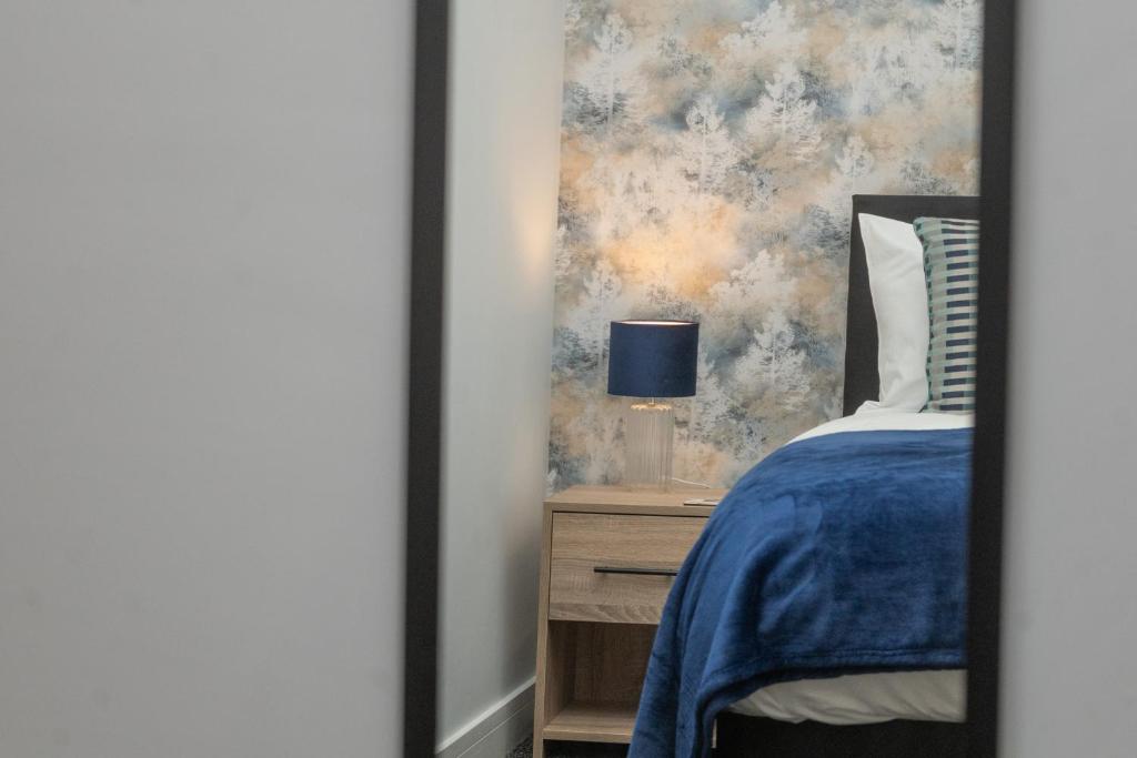 a bedroom with a blue bed and a night stand with a lamp at Historical Holmehill Lodge in Dunblane