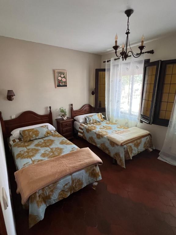 1 dormitorio con 2 camas y lámpara de araña en Hostal Sabor Fusion, en La Pradera de Navalhorno