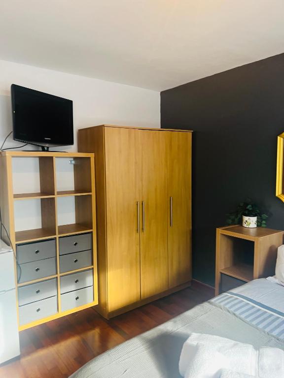 a bedroom with a bed and a cabinet with a television at Lovely private room in Central London next to Hampstead, Camden, and Golders Green in London