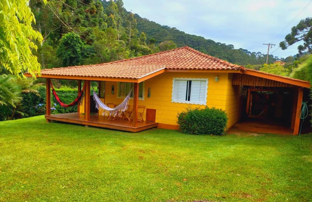 a small yellow house with a hammock in a yard at Casa da Roça in Gonçalves