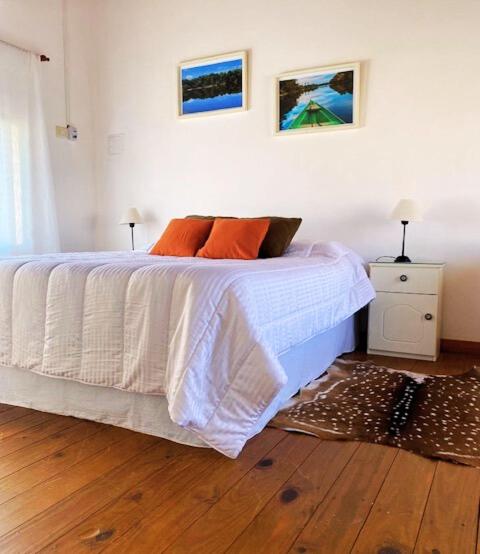 a bedroom with a bed with white sheets and orange pillows at Duplex Reencuentro in Mercedes