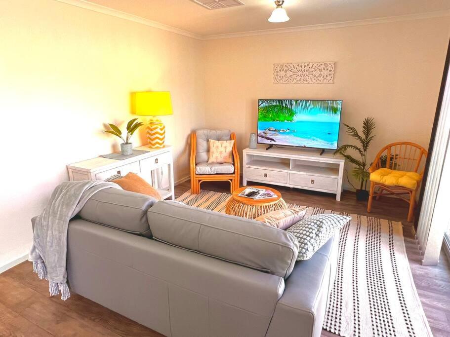 a living room with a couch and a flat screen tv at Seaside Sanctuary Port Noarlunga in Port Noarlunga South