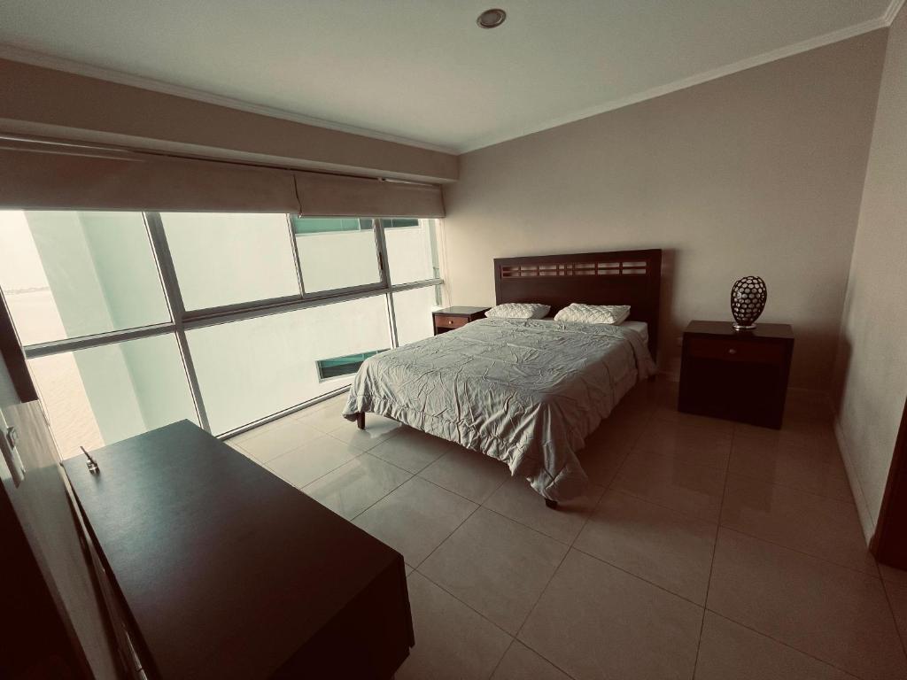 1 dormitorio con cama y ventana grande en Suite frente al río en Puerto Santa Ana Riverfront en Guayaquil
