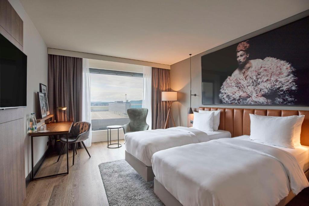 um quarto de hotel com duas camas e uma secretária e uma janela em Radisson Blu Hotel Zurich Airport em Kloten