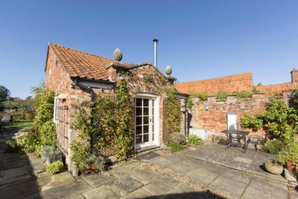 an old brick house with a patio in front of it at The Writer's Studio (stylish garden guesthouse) 