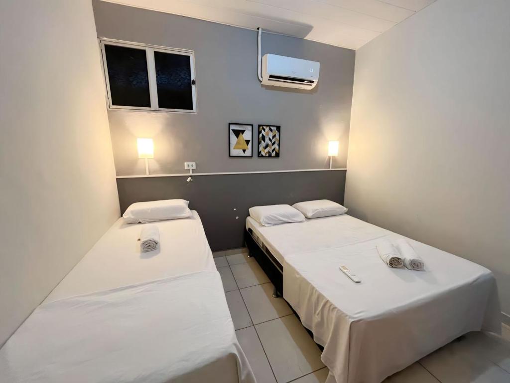 Duas camas num pequeno quarto com paredes brancas em Apartamento Simples e completo em Maragogi