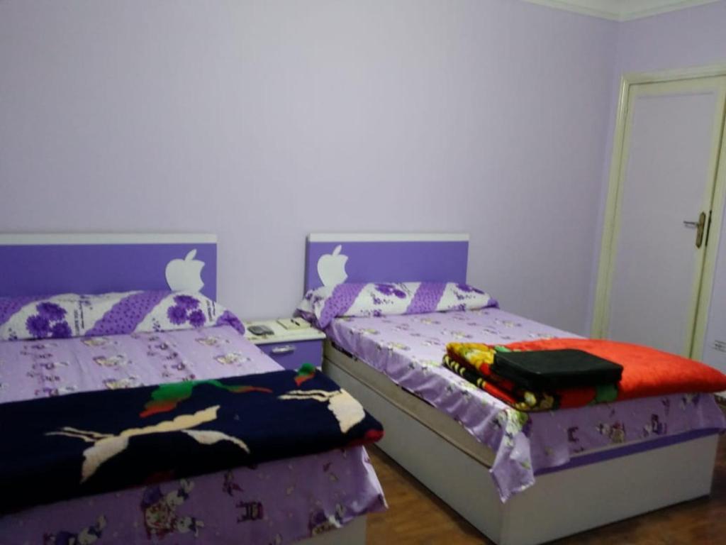 two twin beds in a bedroom with purple walls at شقة مفروشة للايجار علي عباس العقاد الرئيسي in Cairo