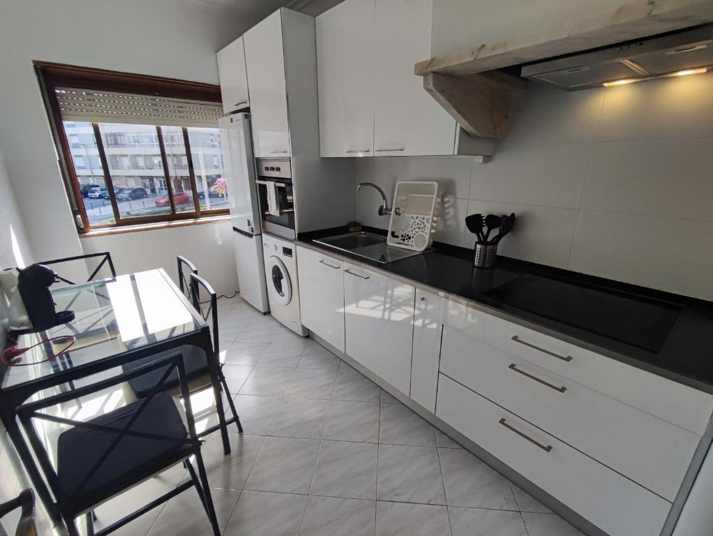 a kitchen with white cabinets and a table with chairs at Sintra, T3 with terrace in Massama, Queluz, Sintra in Queluz