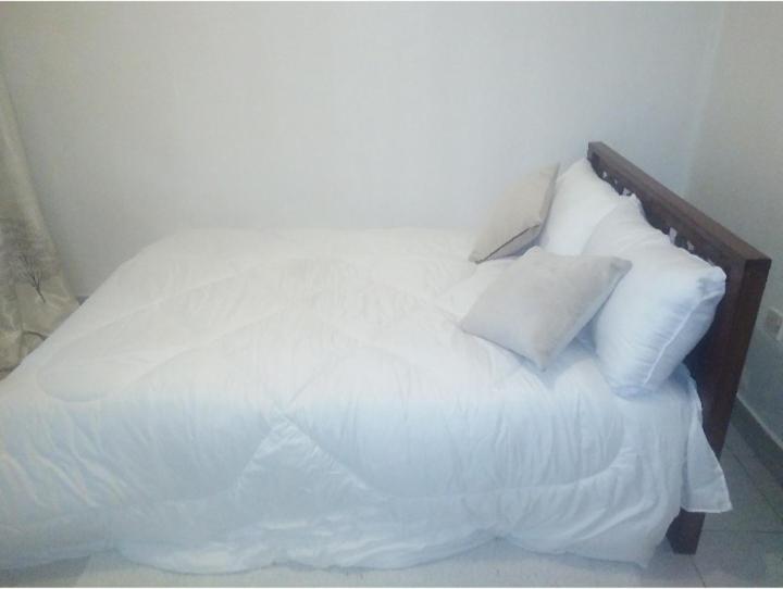 - un lit blanc avec des oreillers blancs au-dessus dans l'établissement Pk cosy apartment, à Nairobi