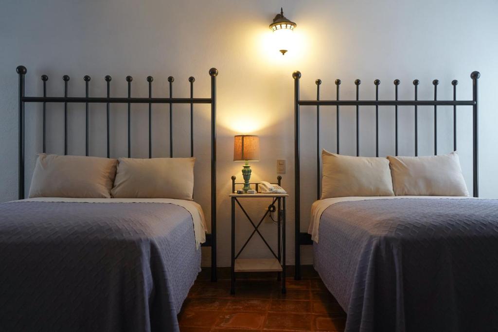 een slaapkamer met 2 bedden en een tafel met een lamp bij Hotel Real de Leyendas in Guanajuato