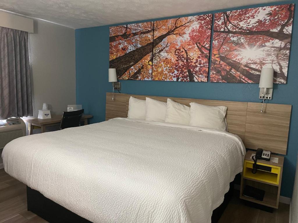 ein Schlafzimmer mit einem Bett mit einem großen Gemälde an der Wand in der Unterkunft Days Inn by Wyndham Warrensburg in Warrensburg
