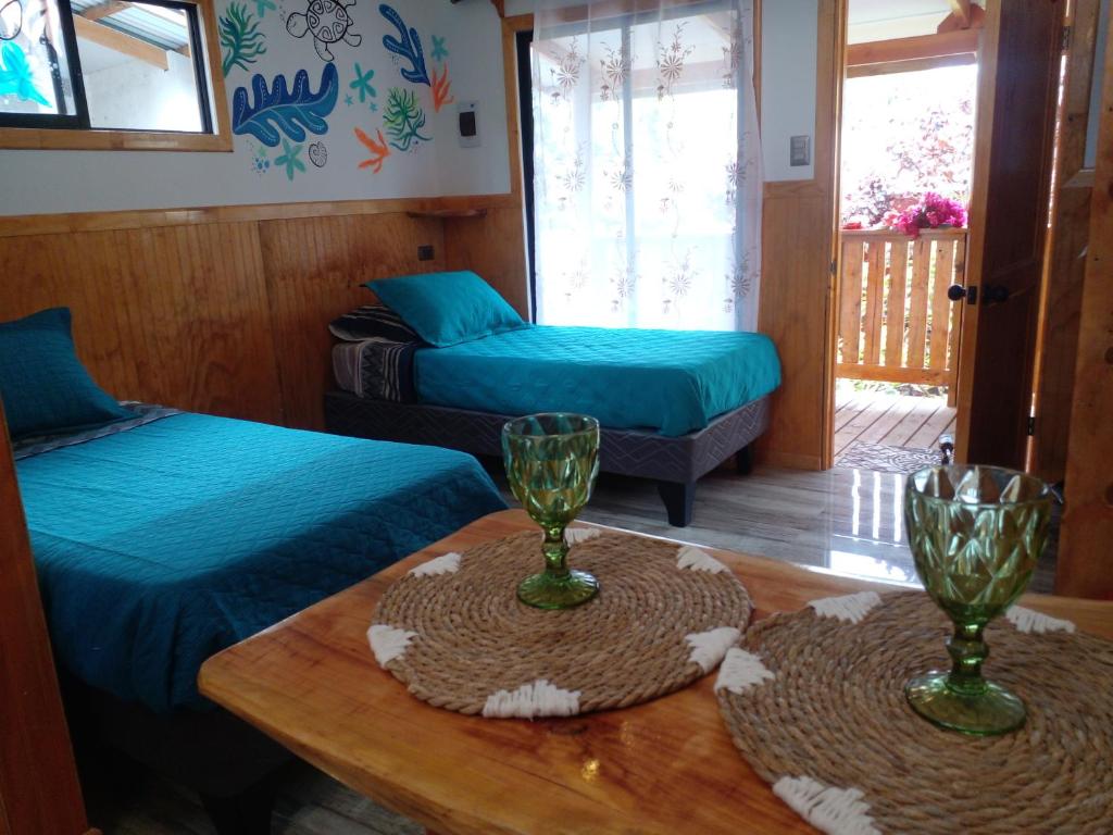 a room with two beds and a table with glasses on it at HARE O HAUPIANO in Hanga Roa