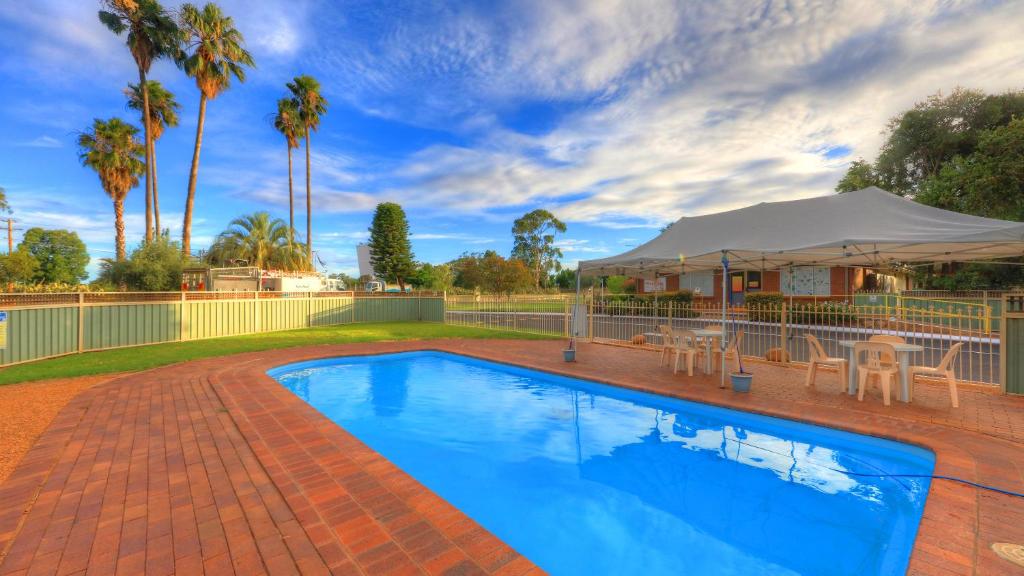 una piscina con una mesa y una tienda en West View Caravanpark, en Dubbo