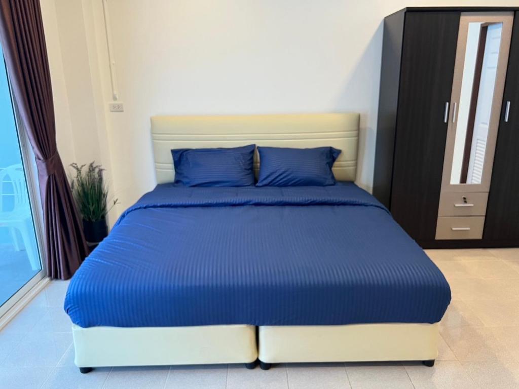 a bed with blue pillows in a bedroom at AB House in Ban Thung Thong