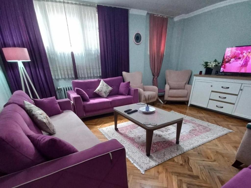 uma sala de estar com sofás roxos e uma mesa em Grand appartement 21 em Istambul
