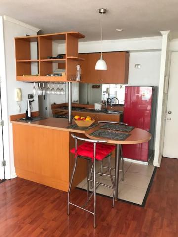a kitchen with a table and two stools in it at Condominio PLaza Club in Temuco