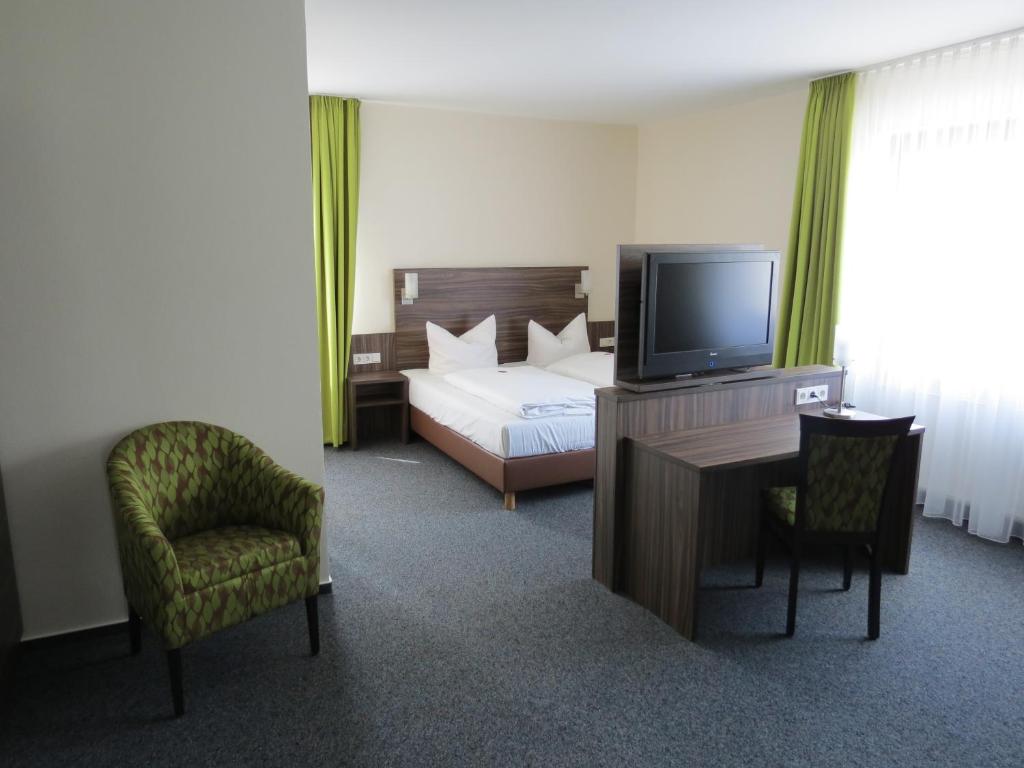Schlafzimmer mit einem Bett, einem TV und einem Schreibtisch in der Unterkunft Hotel-Restaurant Zum Stern in Baumholder