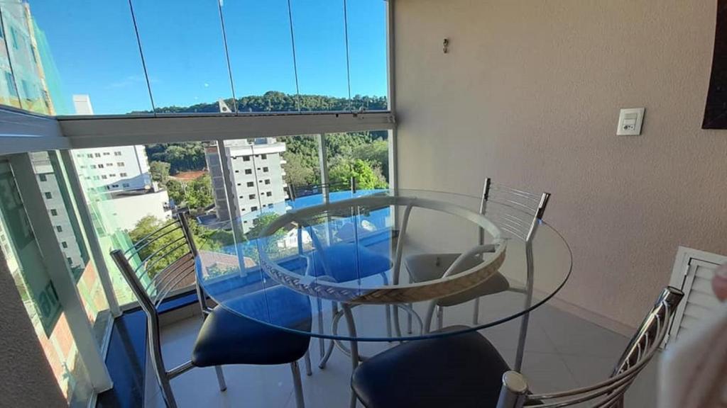 a glass table and chairs in a room with a window at Excelente apto 501, apenas 5 min das Thermas in Piratuba