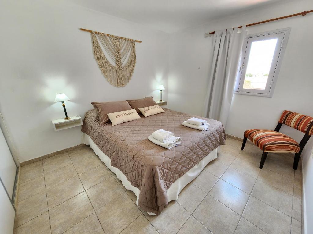 1 dormitorio con 1 cama, 1 silla y 1 ventana en Depto La Leda en Almafuerte
