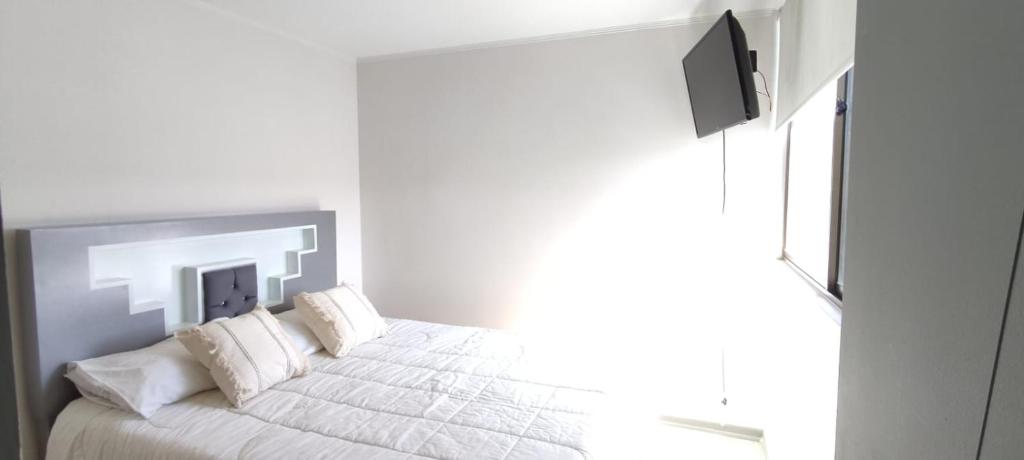 Dormitorio blanco con cama con sábanas y almohadas blancas en Apartamento condominio Arica, en Arica