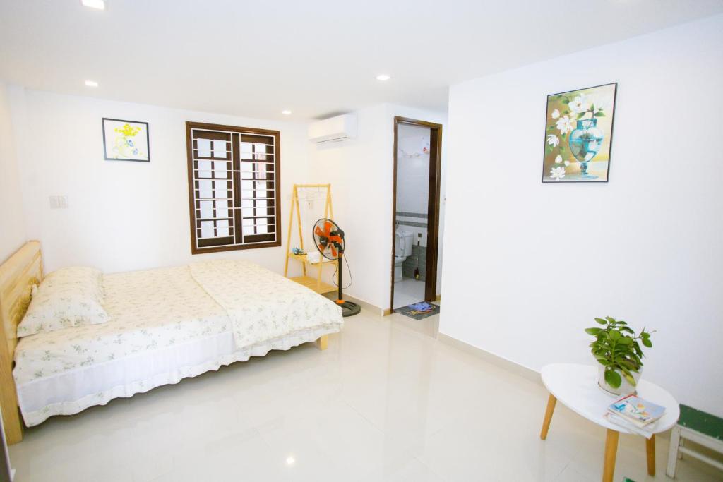 een witte slaapkamer met een bed en een tafel bij Kennpi homestay - phòng lẻ hoặc nguyên căn in Hue