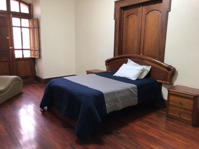 a bedroom with a bed with a wooden headboard at Hospedaje las Primicias 104 in Riobamba