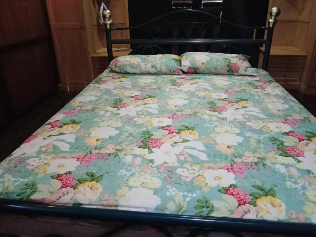 1 cama con colcha floral y almohadas en Azli homestay, en Tampin