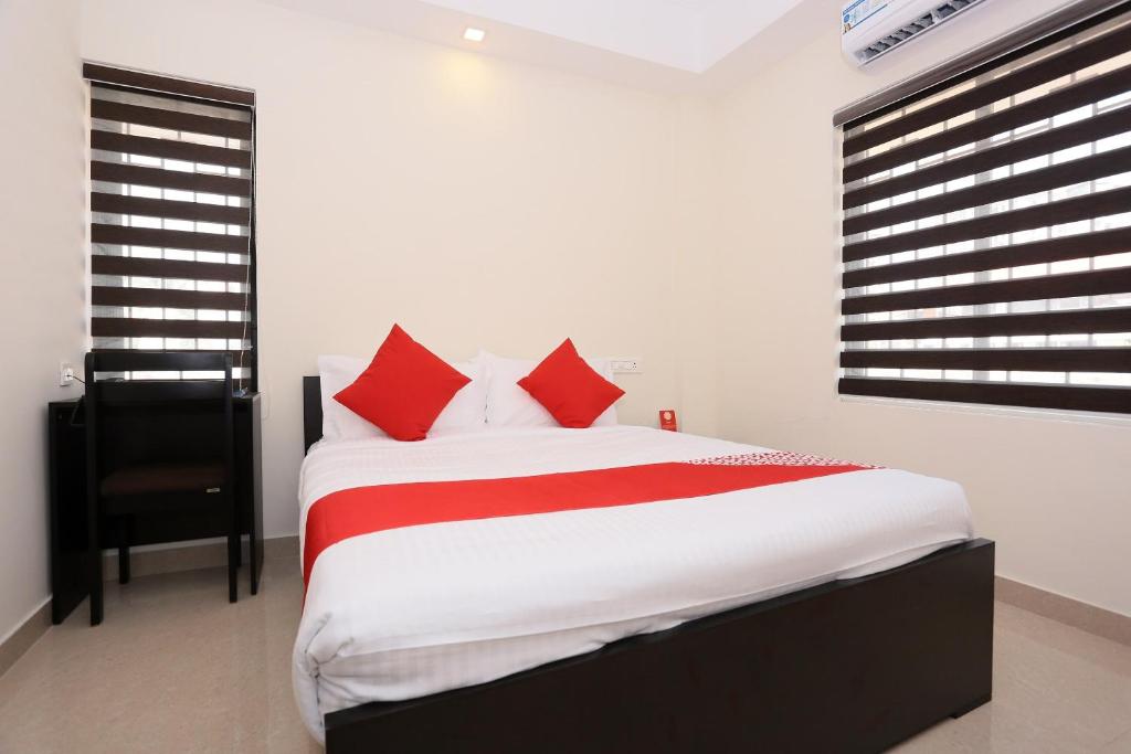 a bedroom with a large bed with red pillows at Hotel Better Inn in Ernakulam