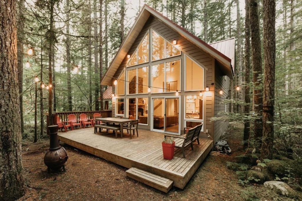 een klein huis in het bos met een houten terras bij 40GS – WiFi - WithD – Hot Tub - Sleeps 8 cabin in Glacier