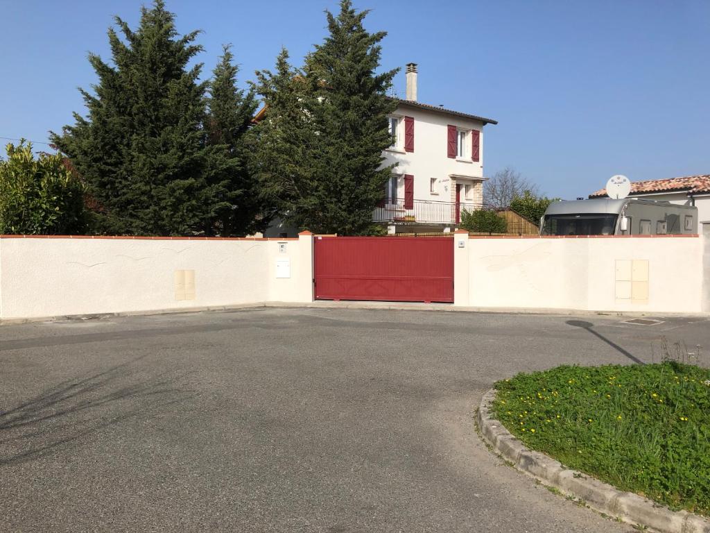 a driveway with a red gate in front of a house at Villa La Libellule Grand Jardin et Parking Privé in Toulouse