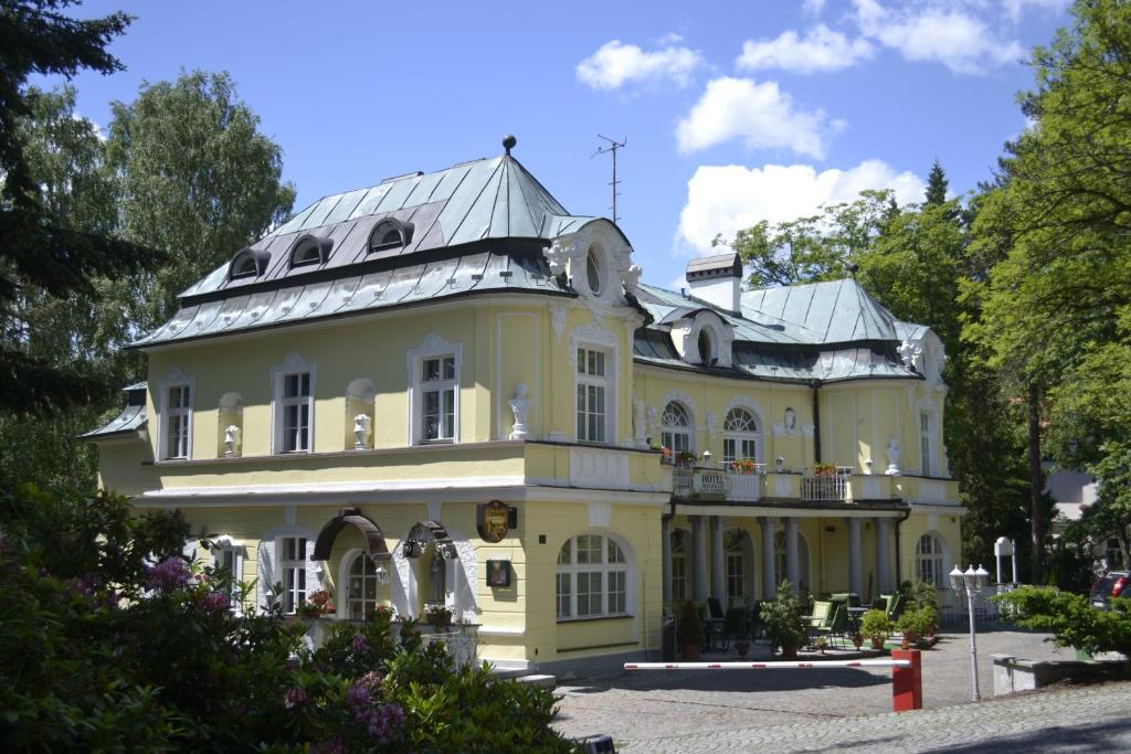 a large yellow house with a tin roof at Hotel Saint Antonius in Mariánské Lázně