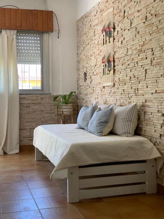 a bed in a room with a brick wall at CASA CANGAS in Belén de Escobar