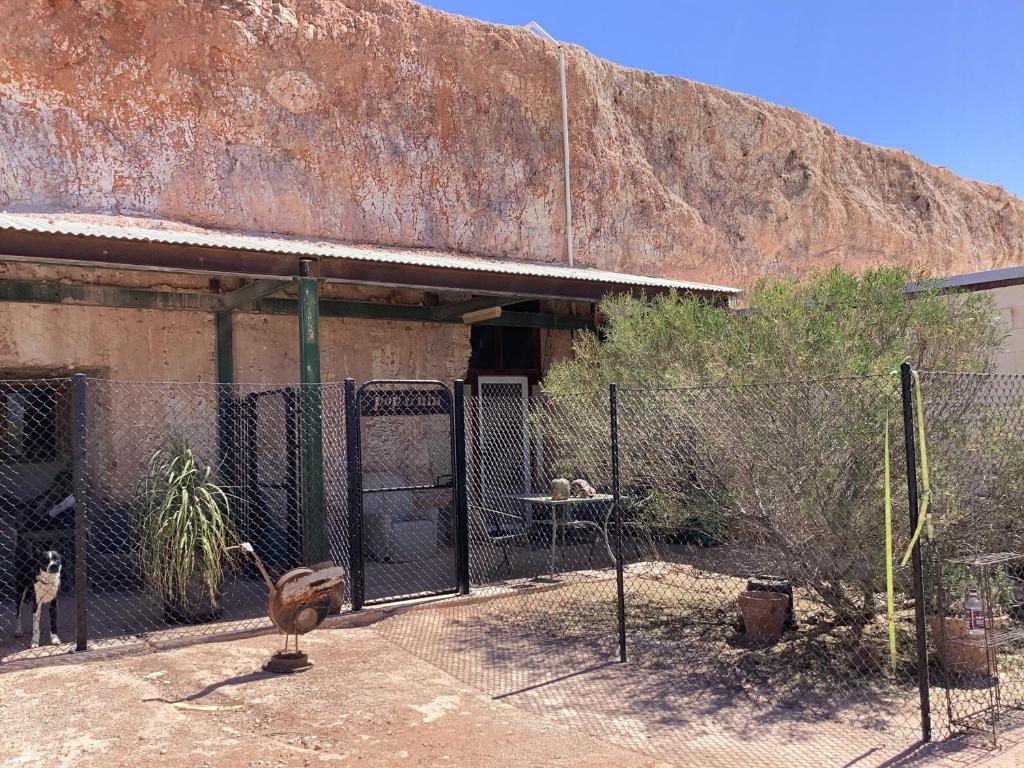 a fence in front of a building with animals in it at Pop’n’nin Dugout Accommodation at Coober Pedy Views in Coober Pedy