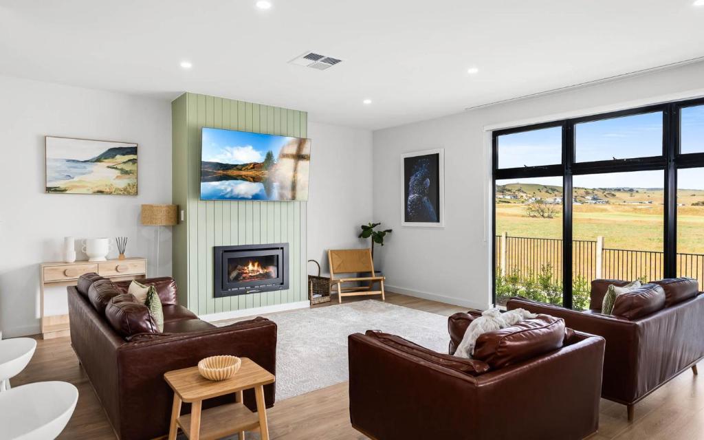 een woonkamer met 2 banken en een open haard bij Golden Views at Normanville 36 Union Road in Normanville