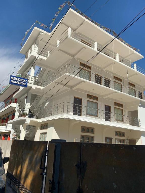 a white building with a fence in front of it at Mondruk Homestay in Dirang Dzong