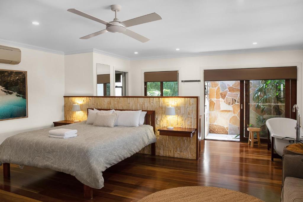 a bedroom with a large bed with a ceiling fan at Away Guesthouse- Away on Shirley Lane in Byron Bay