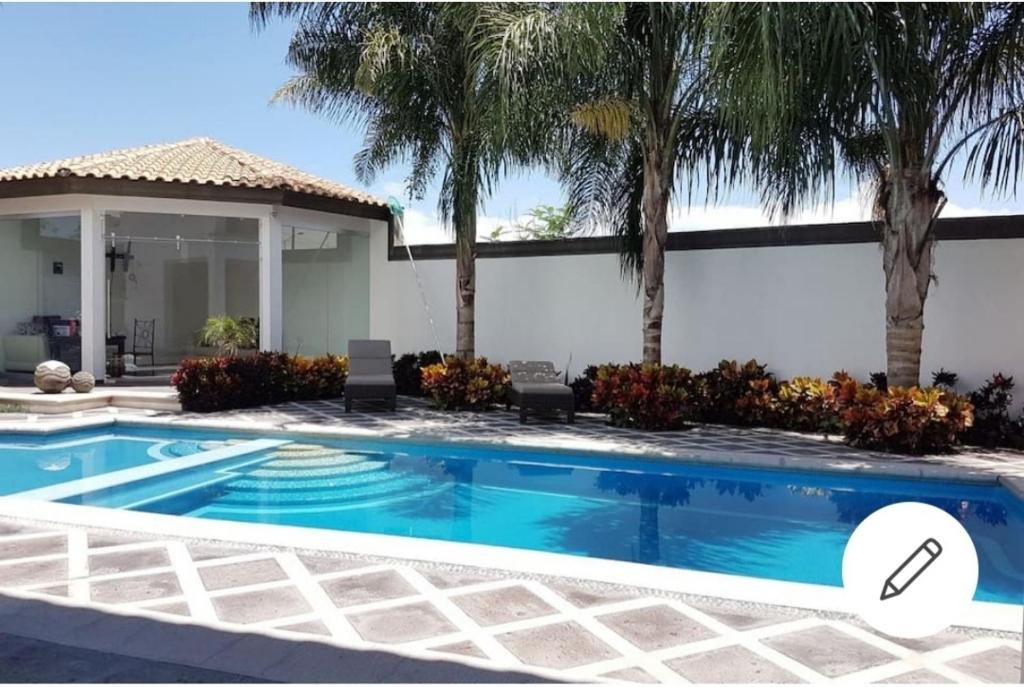 a swimming pool in front of a house with palm trees at Casa Tamarindo in Alpuyeca